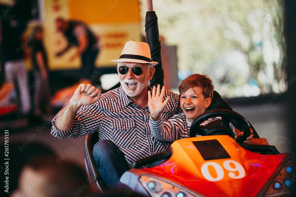 Grandfather and grandson having fun in a bumper car at an amusement park